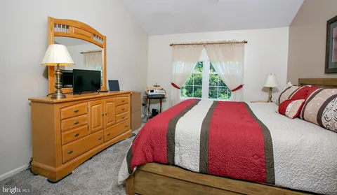a bedroom with a bed and a flat tv screen on dresser