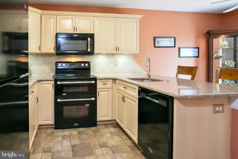 a kitchen with stainless steel appliances granite countertop a stove top oven a sink dishwasher and a microwave oven on the stove