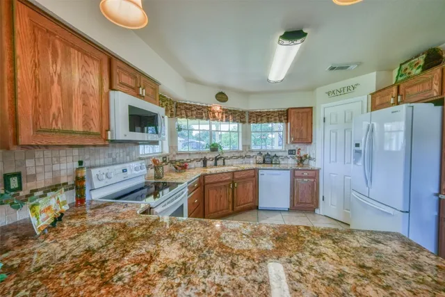 a kitchen with stainless steel appliances granite countertop a refrigerator stove top oven and sink