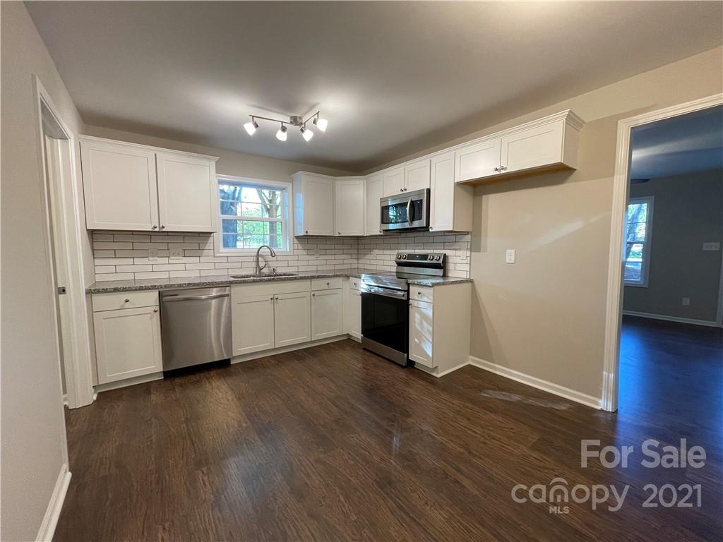 1601 Rushing Street Monroe, NC 28112 - Photo 7 of 21 a kitchen with stainless steel appliances granite countertop a stove top oven a sink and a refrigerator