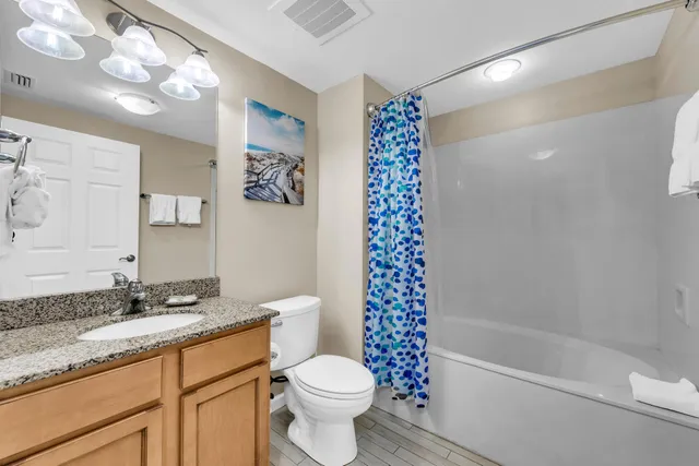 a bathroom with a granite countertop sink a toilet a mirror a vanity and bathtub