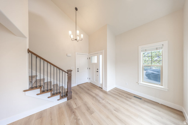 2169 Orchard Pines Loop East Bountiful, UT 84010 - Photo 13 of 32 Entryway featuring light wood-finish flooring, a contemporary chandelier, and a white paneled door with sidelight
