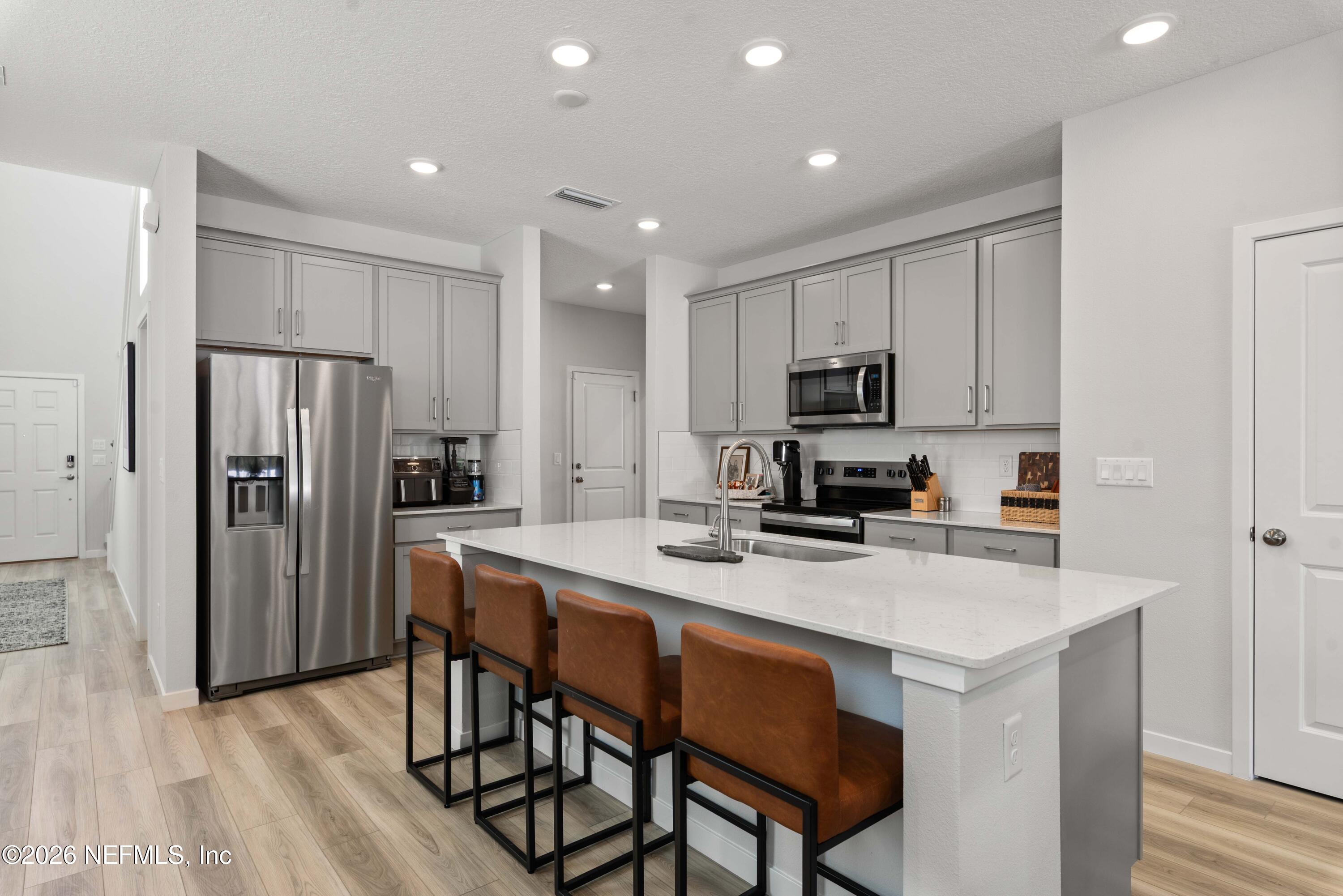 96245 Broadmoore Road Fernandina Beach, FL 32034 - Photo 6 of 33 a kitchen with a refrigerator a stove a microwave and island with wooden floor
