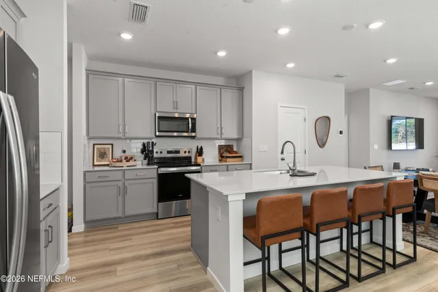 a kitchen with stainless steel appliances granite countertop a table chairs sink refrigerator and cabinets