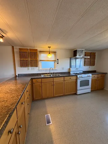 a kitchen with stainless steel appliances a sink dishwasher stove refrigerator and cabinets