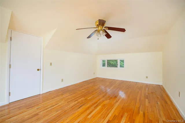 an empty room with wooden floor ceiling fan and window