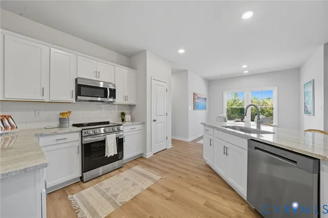 a large white kitchen with lots of counter space and stainless steel appliances