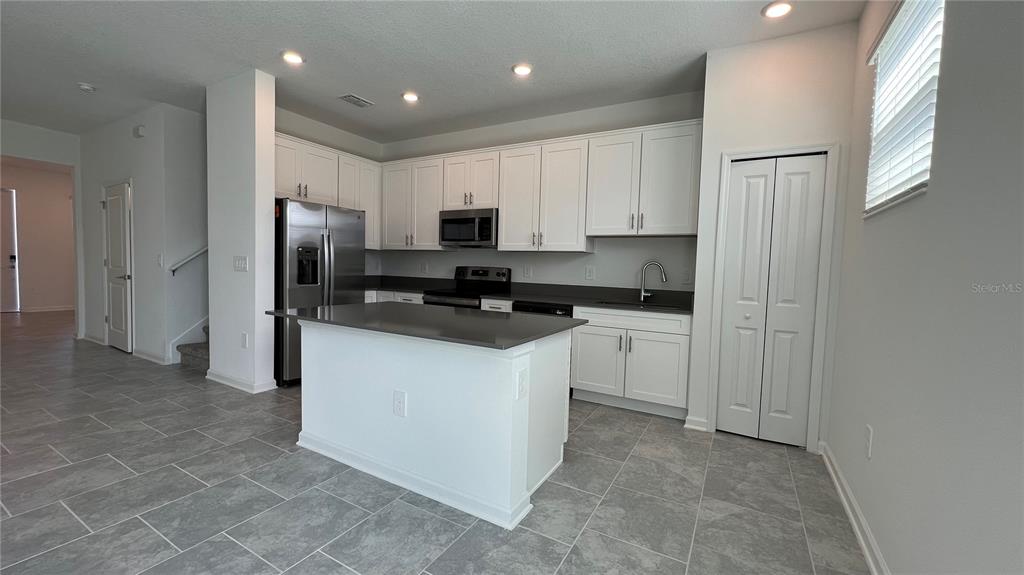 2396 Brook Marsh Loop Kissimmee, FL 34747 - Photo 12 of 29 a kitchen with a refrigerator a stove top oven a sink and cabinets