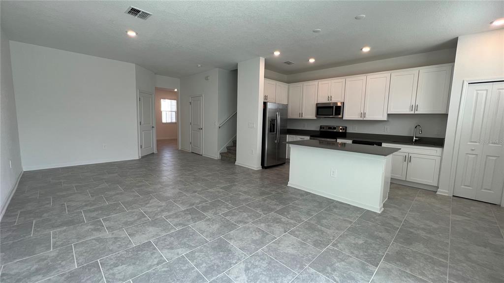 2396 Brook Marsh Loop Kissimmee, FL 34747 - Photo 8 of 29 a kitchen with stainless steel appliances granite countertop a stove a sink a refrigerator a microwave and cabinets