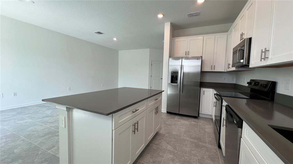 2396 Brook Marsh Loop Kissimmee, FL 34747 - Photo 9 of 29 a kitchen with stainless steel appliances granite countertop a kitchen island a stove a refrigerator and a sink