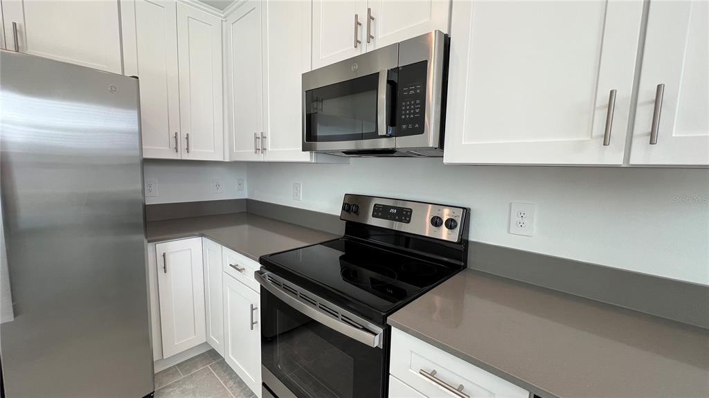 2396 Brook Marsh Loop Kissimmee, FL 34747 - Photo 10 of 29 a kitchen with stainless steel appliances granite countertop white cabinets and a stove top oven