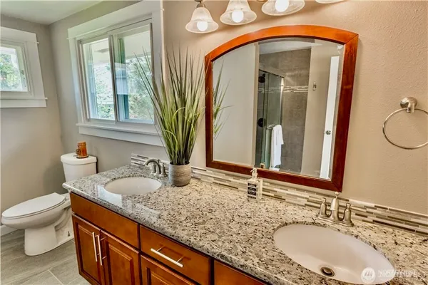 a bathroom with a granite countertop sink a toilet and mirror