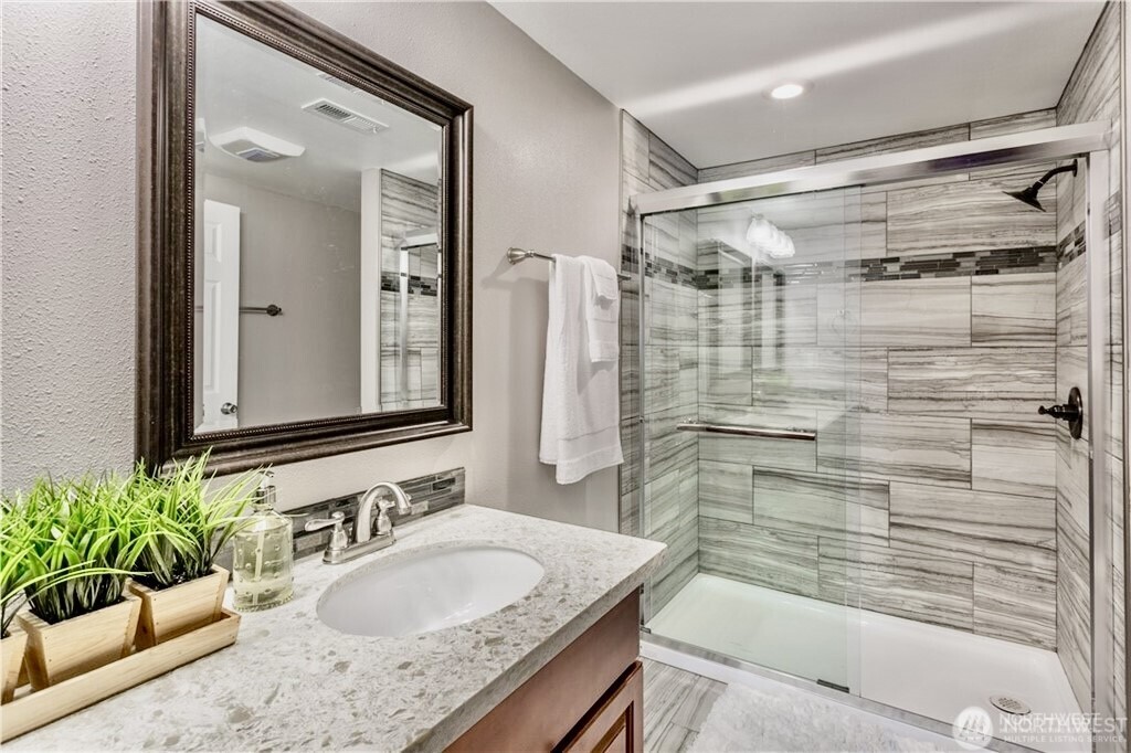 2241 South 252nd Street Des Moines, WA 98198 - Photo 16 of 25 a bathroom with a granite countertop sink a mirror a bathtub and shower