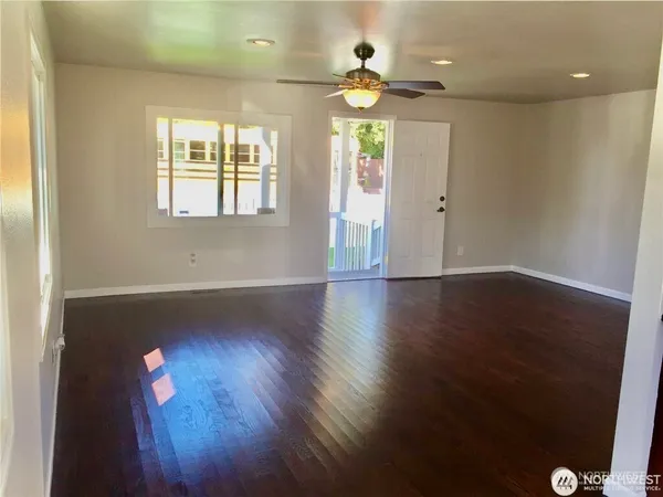 an empty room with wooden floor and windows