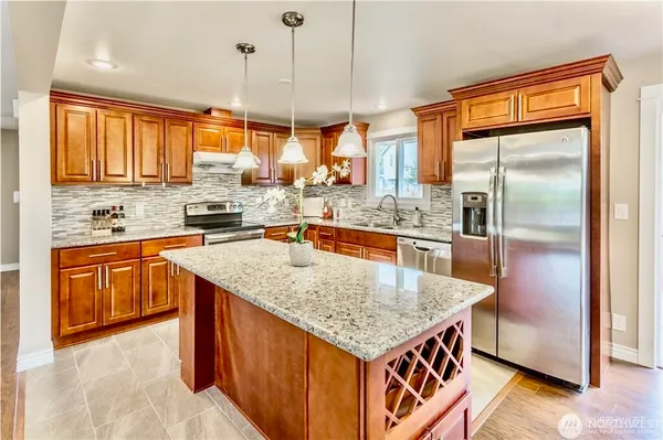 a kitchen with stainless steel appliances granite countertop a sink a refrigerator and wooden cabinets