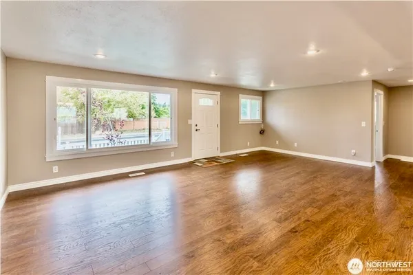 an empty room with wooden floor and windows