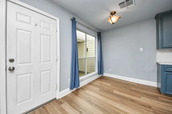 a view of an empty room with a window and wooden floor
