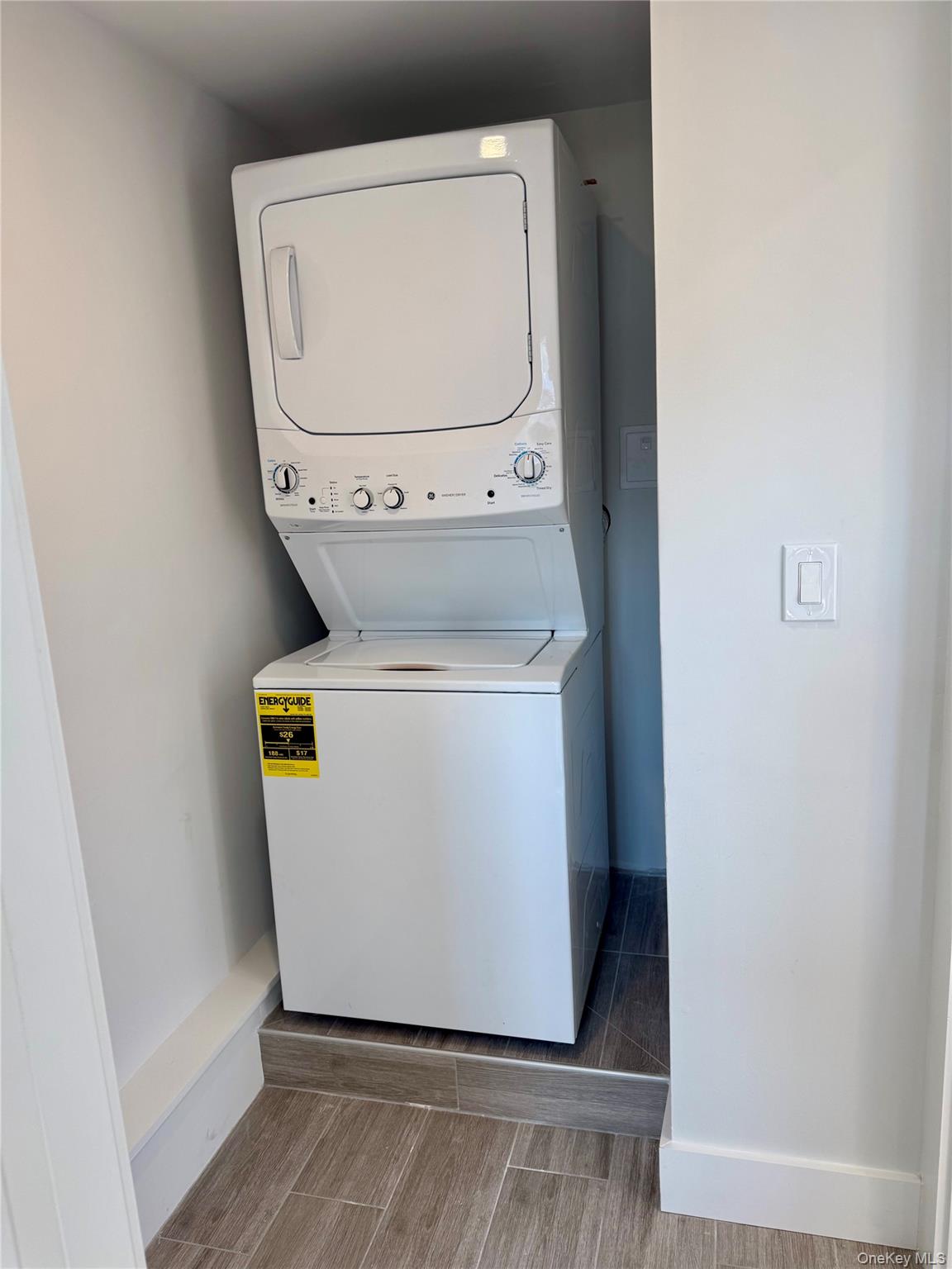 44 Purchase Street, Unit 3L Rye, NY 10580 - Photo 16 of 16 Stackable washer and dryer unit, integrated within a tiled alcove featuring wood-styled flooring