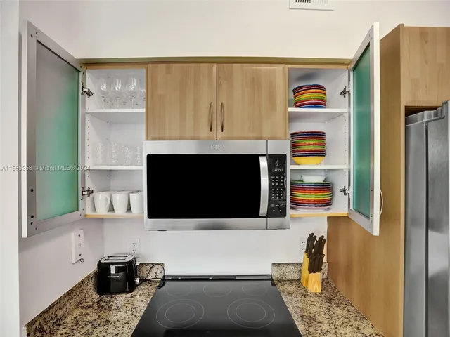 a kitchen with stainless steel appliances kitchen island granite countertop a refrigerator and microwave