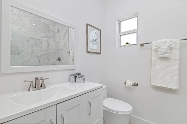 a bathroom with a toilet a sink a mirror and a shower