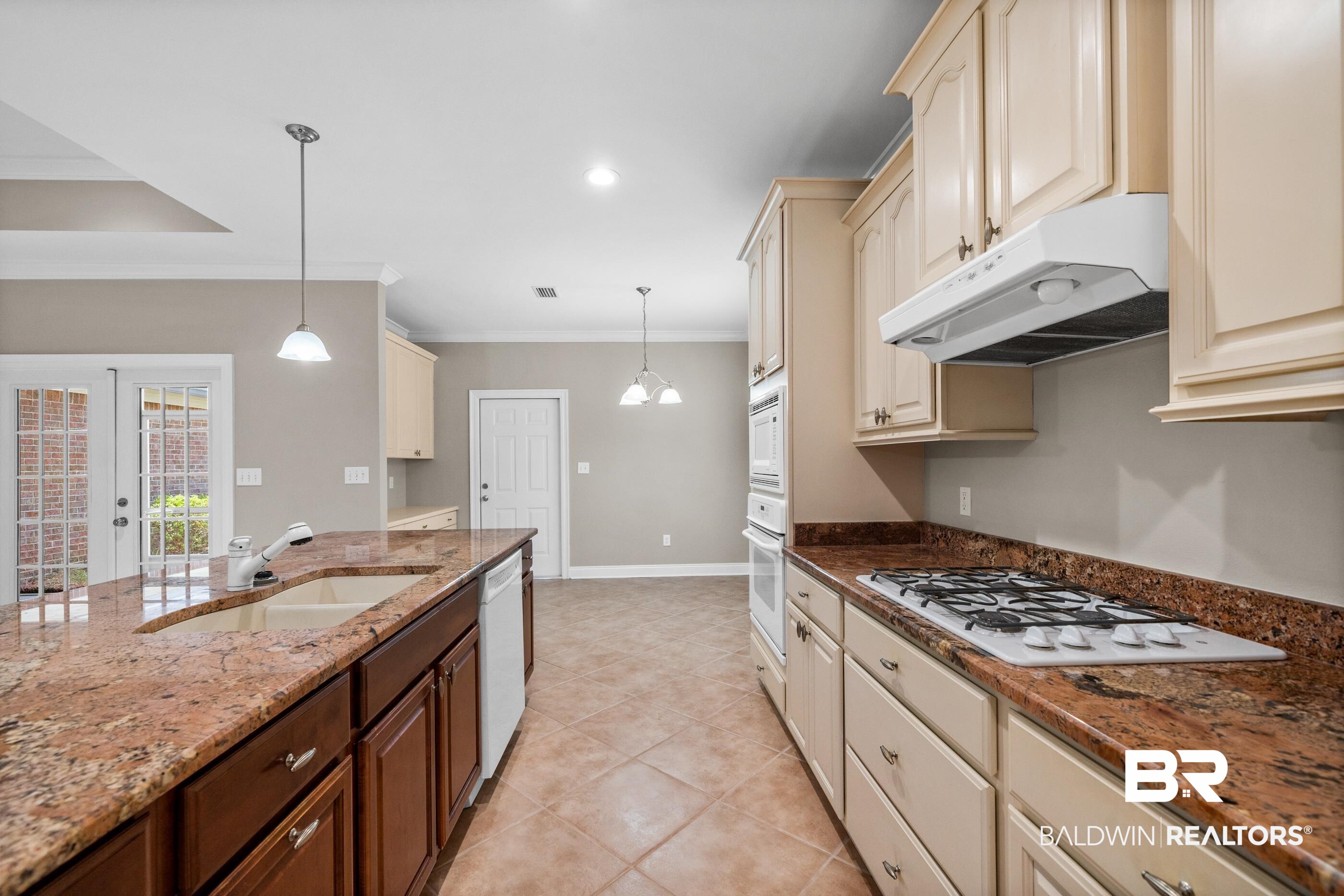 303 Savannah Circle Foley, AL 36535 - Photo 12 of 34 Kitchen featuring an expansive island with an undermount sink, granite countertops, tile flooring, and integrated wall ovens