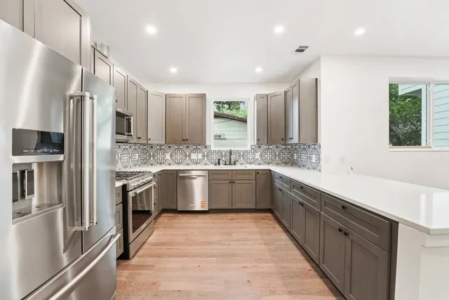 a large kitchen with stainless steel appliances kitchen island granite countertop a refrigerator and a sink