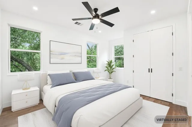 an empty room with wooden floor a ceiling fan and windows