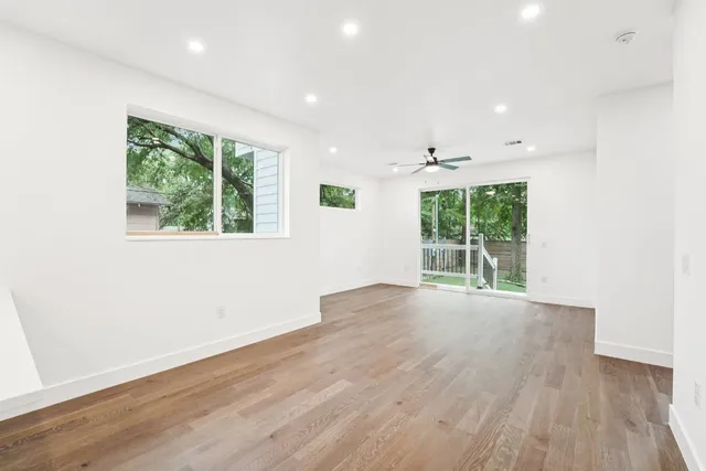 an empty room with wooden floor and windows