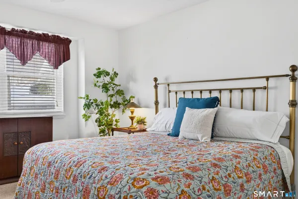 a bedroom with a bed and a potted plant