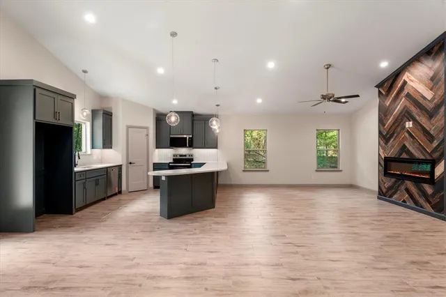 a kitchen with stainless steel appliances kitchen island granite countertop a stove top oven a sink a dining table and chairs