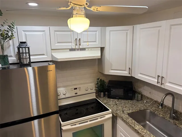 a kitchen with granite countertop a sink stainless steel appliances and cabinets