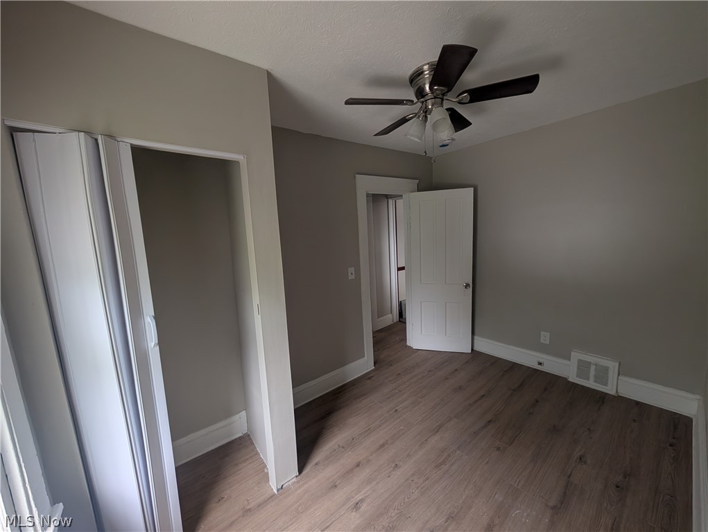 7515 Ottawa Road Cleveland, OH 44105 - Photo 17 of 21 Neutral-toned interior featuring wood-finish flooring, a ceiling fan with light fixture, white trim, and a bi-fold closet door