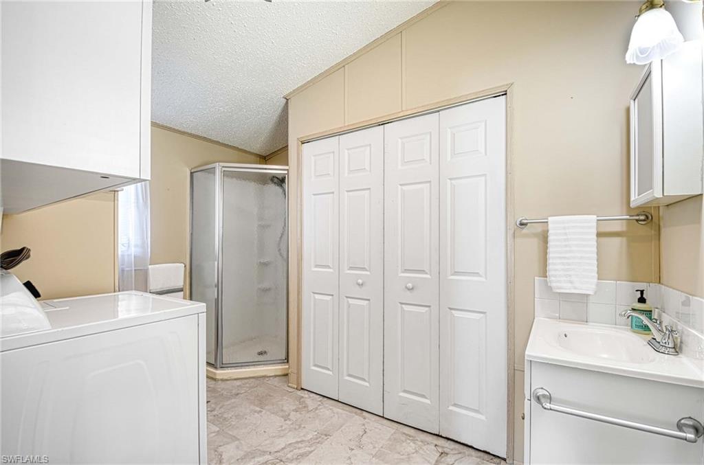 21 Onyx Drive, Unit 21O Naples, FL 34114 - Photo 14 of 30 Washroom featuring washer / clothes dryer, sink, and a textured ceiling