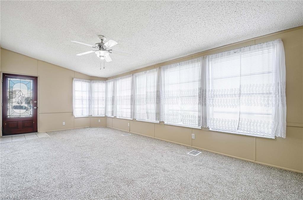 21 Onyx Drive, Unit 21O Naples, FL 34114 - Photo 3 of 30 Spare room featuring a textured ceiling, ceiling fan, light colored carpet, and lofted ceiling