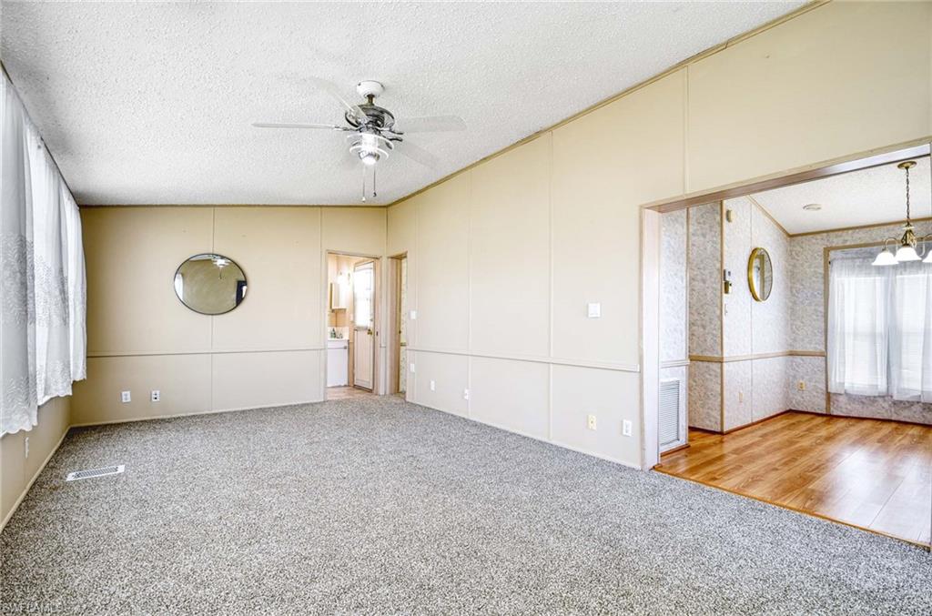 21 Onyx Drive, Unit 21O Naples, FL 34114 - Photo 4 of 30 Unfurnished room with carpet flooring, ceiling fan with notable chandelier, and a textured ceiling