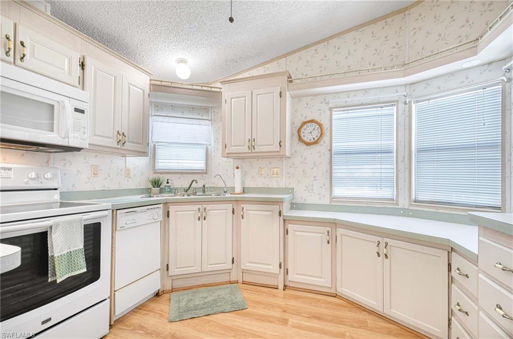 21 Onyx Drive, Unit 21O Naples, FL 34114 - Photo 8 of 30 Kitchen with white cabinetry, sink, light hardwood / wood-style floors, a textured ceiling, and white appliances