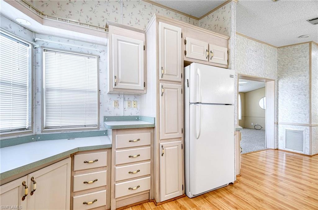 21 Onyx Drive, Unit 21O Naples, FL 34114 - Photo 10 of 30 Kitchen with white refrigerator, crown molding, light hardwood / wood-style floors, and a textured ceiling