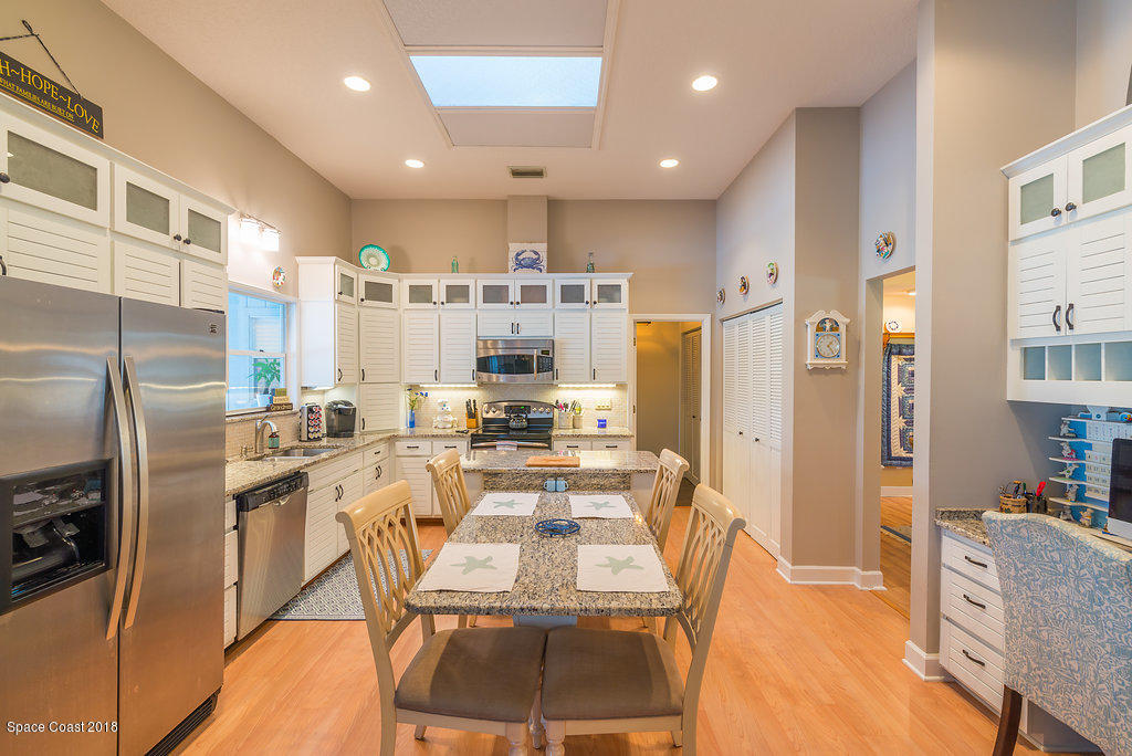 3956 Sparrow Hawk Road Melbourne, FL 32934 - Photo 11 of 34 a kitchen with stainless steel appliances a refrigerator a stove a sink a dining table and chairs