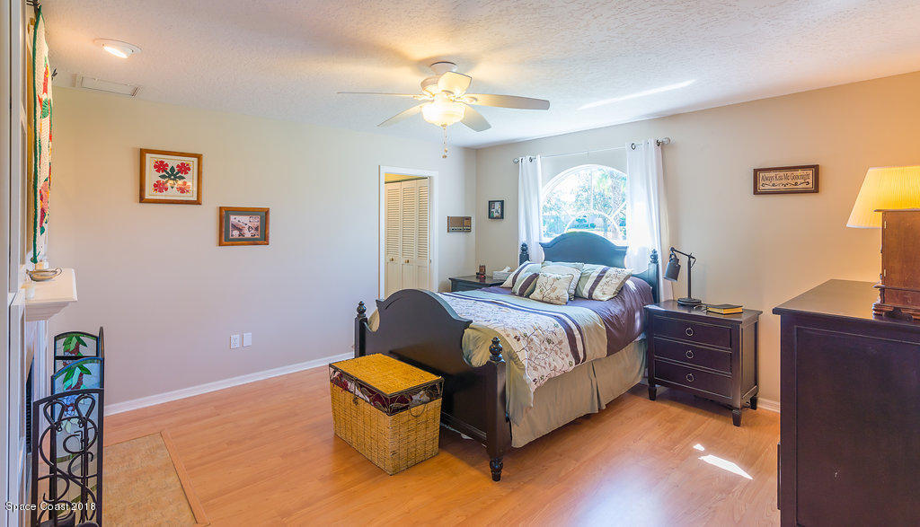 3956 Sparrow Hawk Road Melbourne, FL 32934 - Photo 15 of 34 a bedroom with a bed and a chandelier