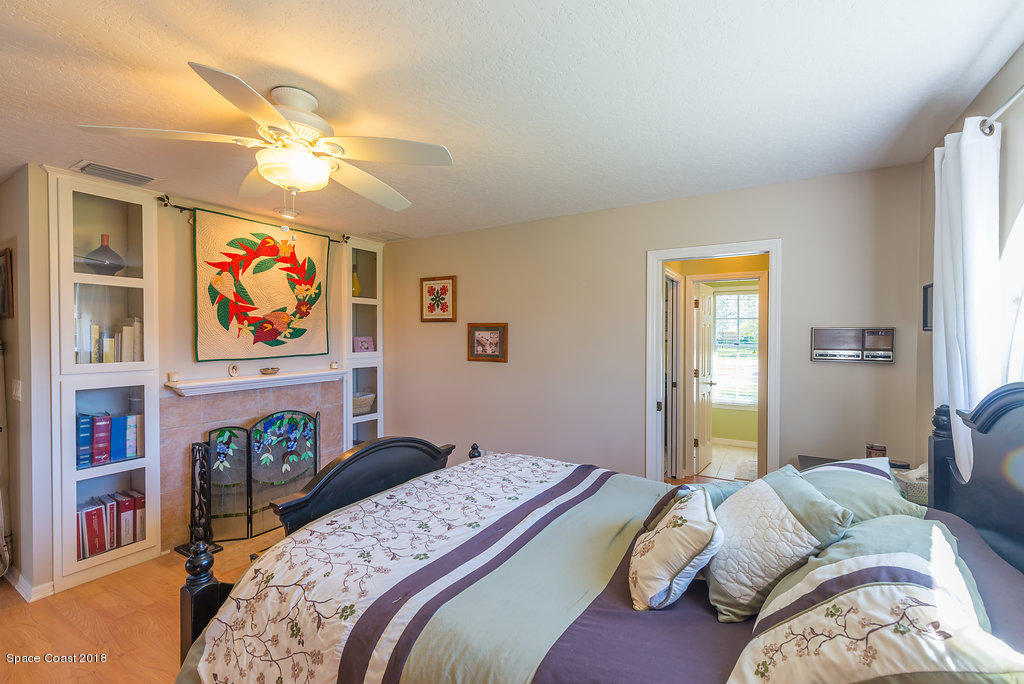 3956 Sparrow Hawk Road Melbourne, FL 32934 - Photo 17 of 34 a bedroom with a bed a dresser and a chandelier