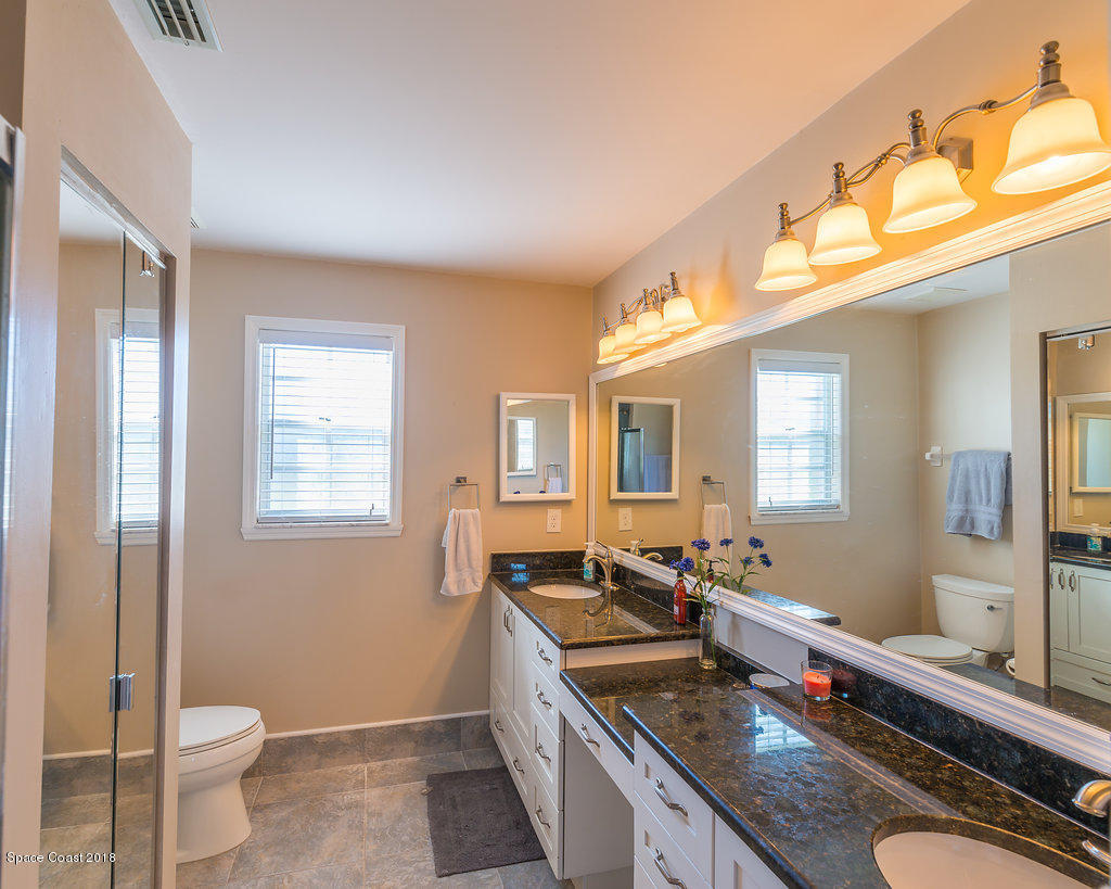 3956 Sparrow Hawk Road Melbourne, FL 32934 - Photo 18 of 34 a spacious bathroom with a granite countertop sink a toilet a mirror and a tub