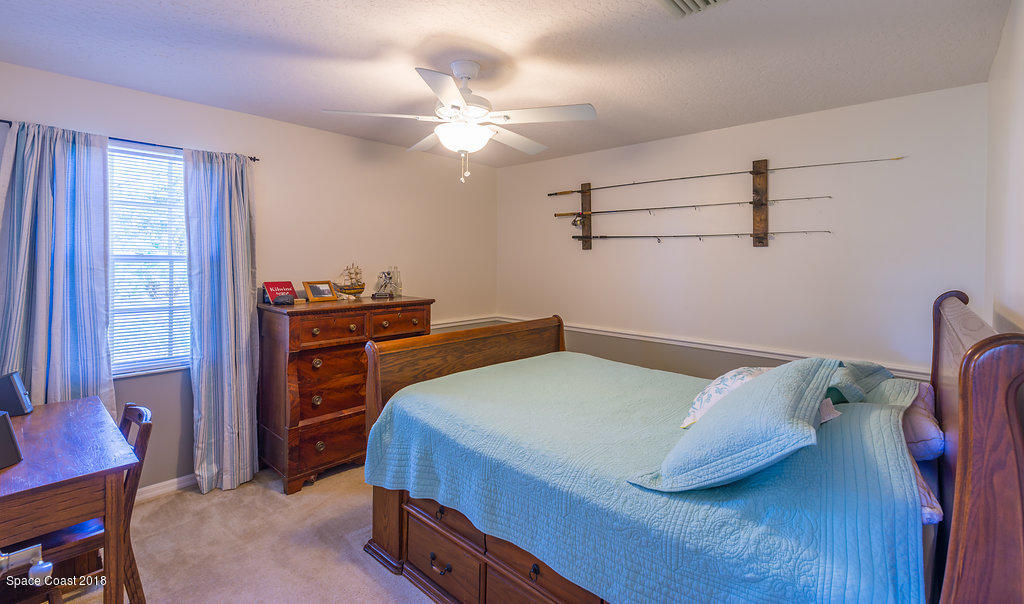 3956 Sparrow Hawk Road Melbourne, FL 32934 - Photo 22 of 34 a bedroom with a bed and a chandelier