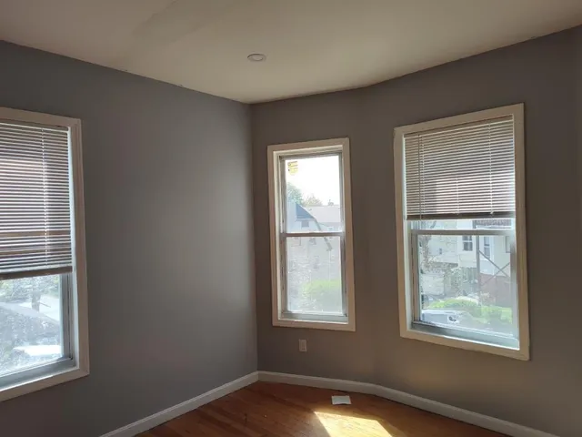 a view of an empty room with wooden floor and windows