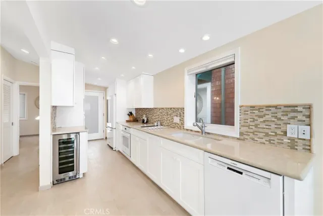 a large white kitchen with a sink and a refrigerator