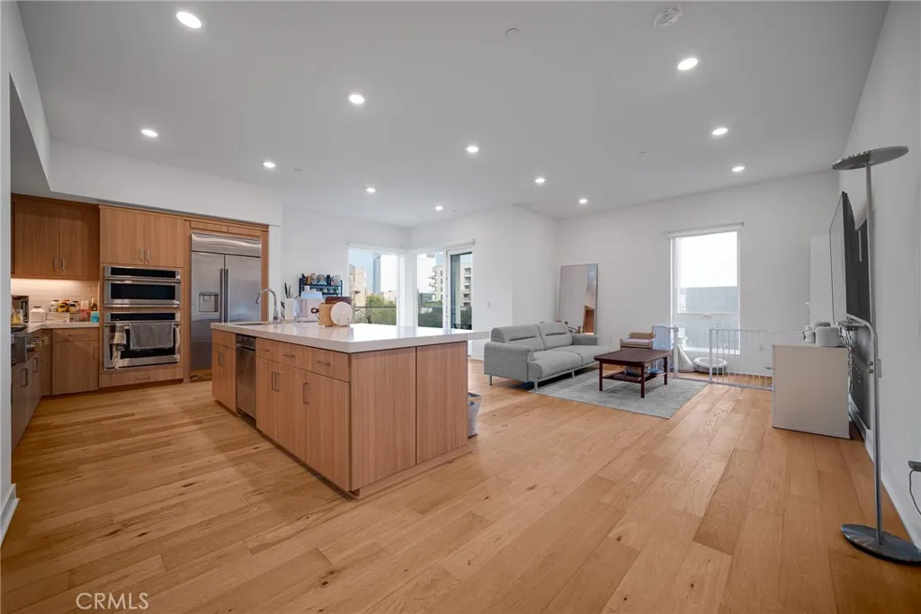 1310 Rivington Irvine, CA 92606 - Photo 6 of 20 a large white kitchen with stainless steel appliances granite countertop a large counter top a couch and a view of living room