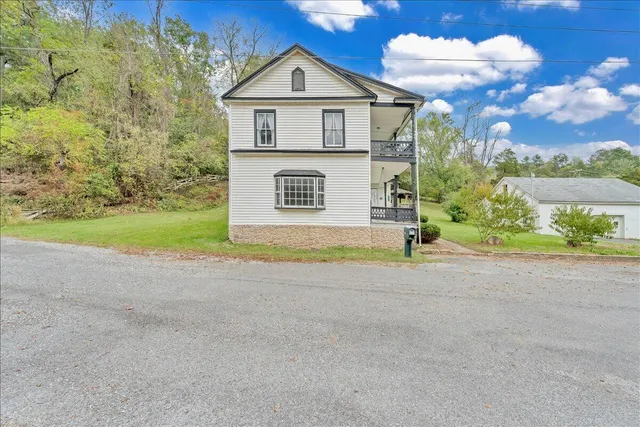 a view of a house with a yard and large tree