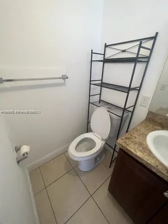 a bathroom with a granite countertop toilet and a sink