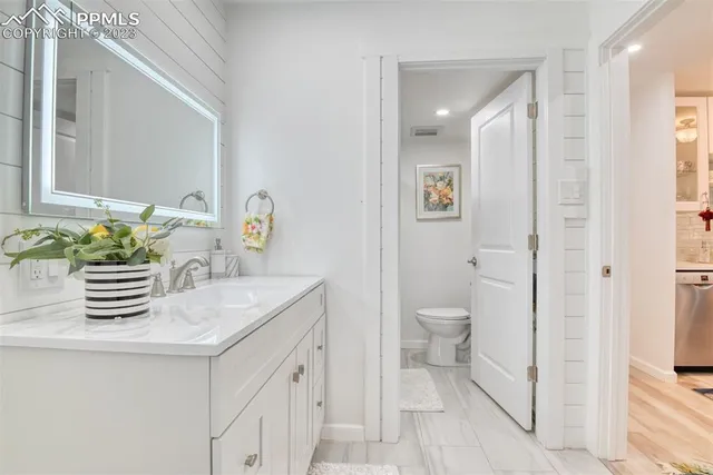 a bathroom with a granite countertop sink a toilet and a mirror