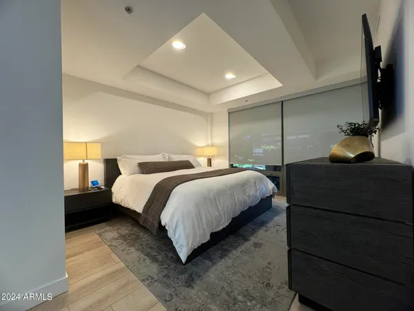 a bedroom with a bed and a flat tv screen on dresser