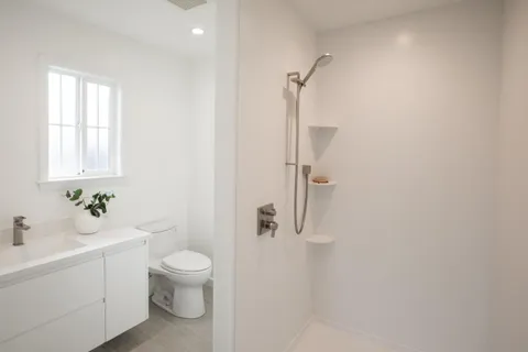 a bathroom with a granite countertop sink a toilet and shower